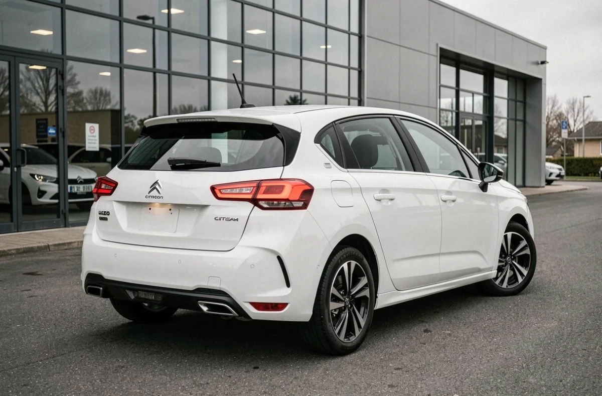 Citroën C4 blanche vue de l'arrière en angle 3/4 dans un parking de concession automobile moderne